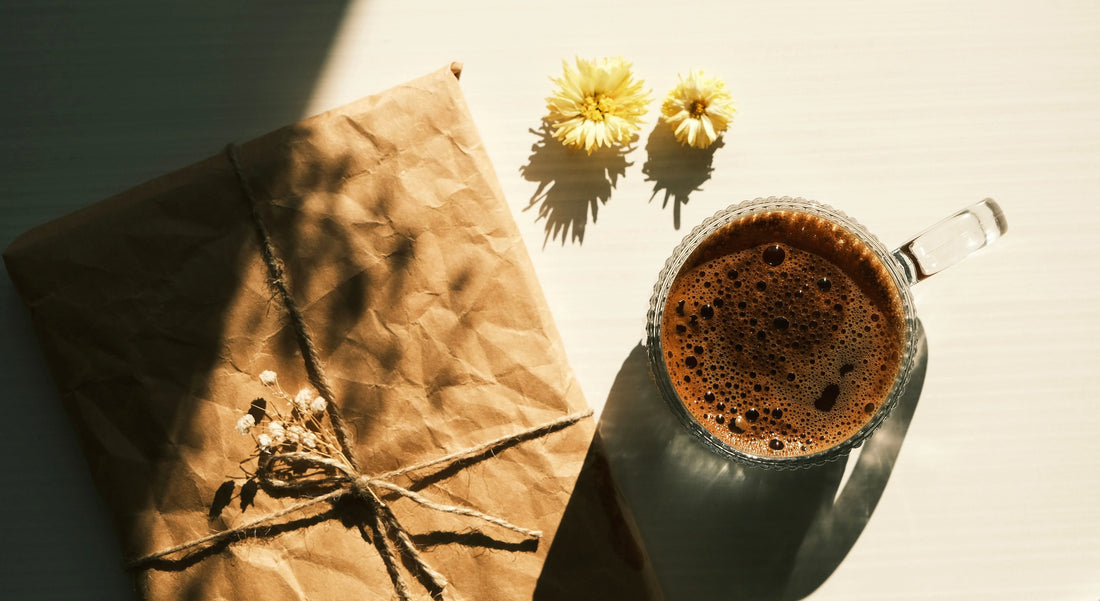 Inslaget paket bredvid en kopp svart kaffe.