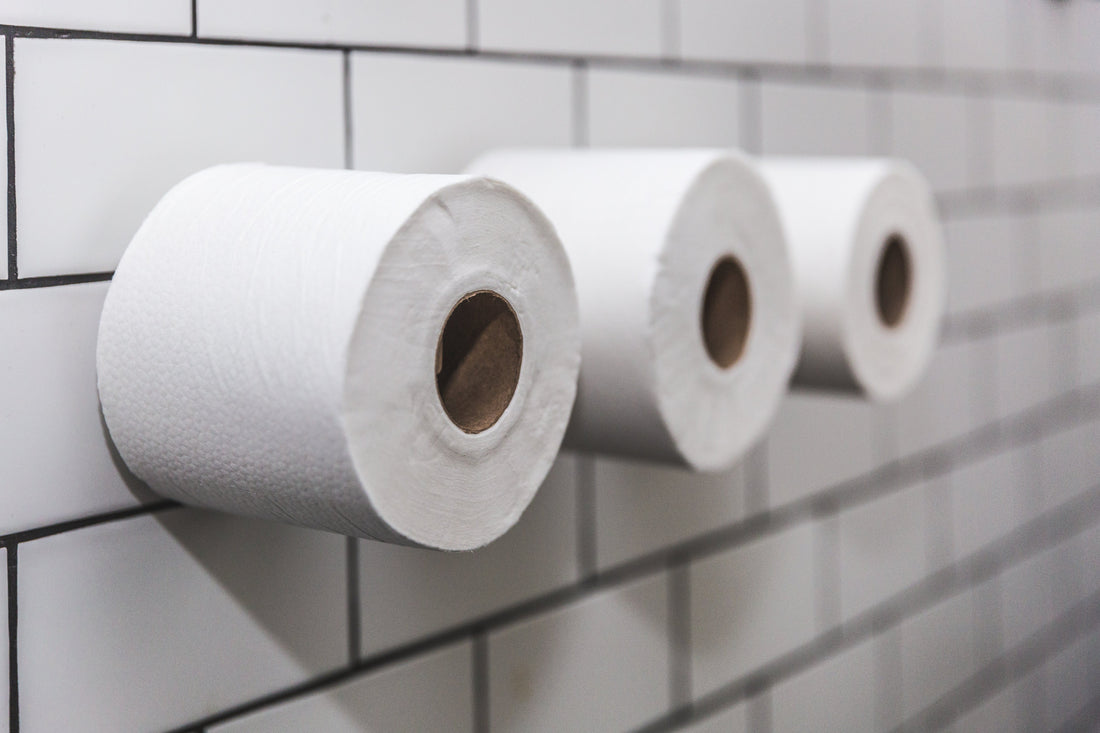 Three rolls of toilet paper mounted on a tiled bathroom wall.