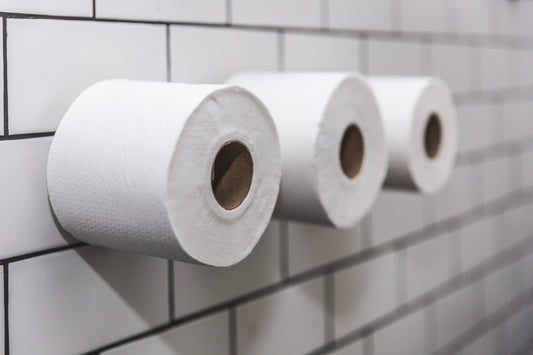 Three rolls of toilet paper mounted on a tiled bathroom wall.