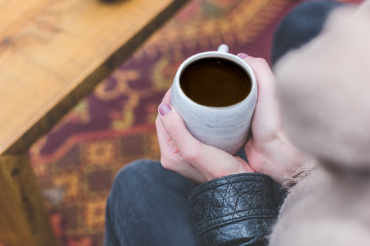 Person som håller en mugg kaffe med en suddig bakgrund.
