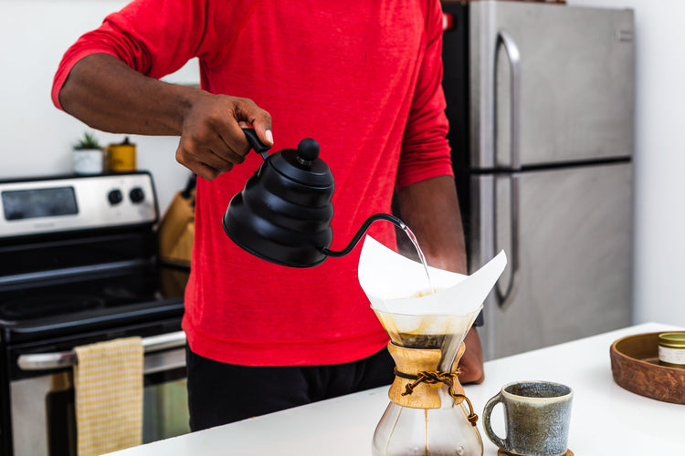 AeroPress Clear coffee maker next to a glass mug of fresh coffee.