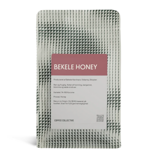 En påse Coffee Collective "Bekele Honey" kaffe från Sidama, Etiopien, med ett vitt och grönt triangelmönster och en malvafärgad etikett.