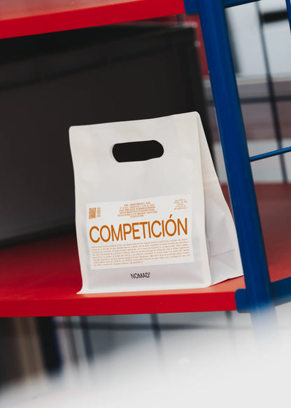 Vit plastpåse med COMPETICION-text på en röd hylla
