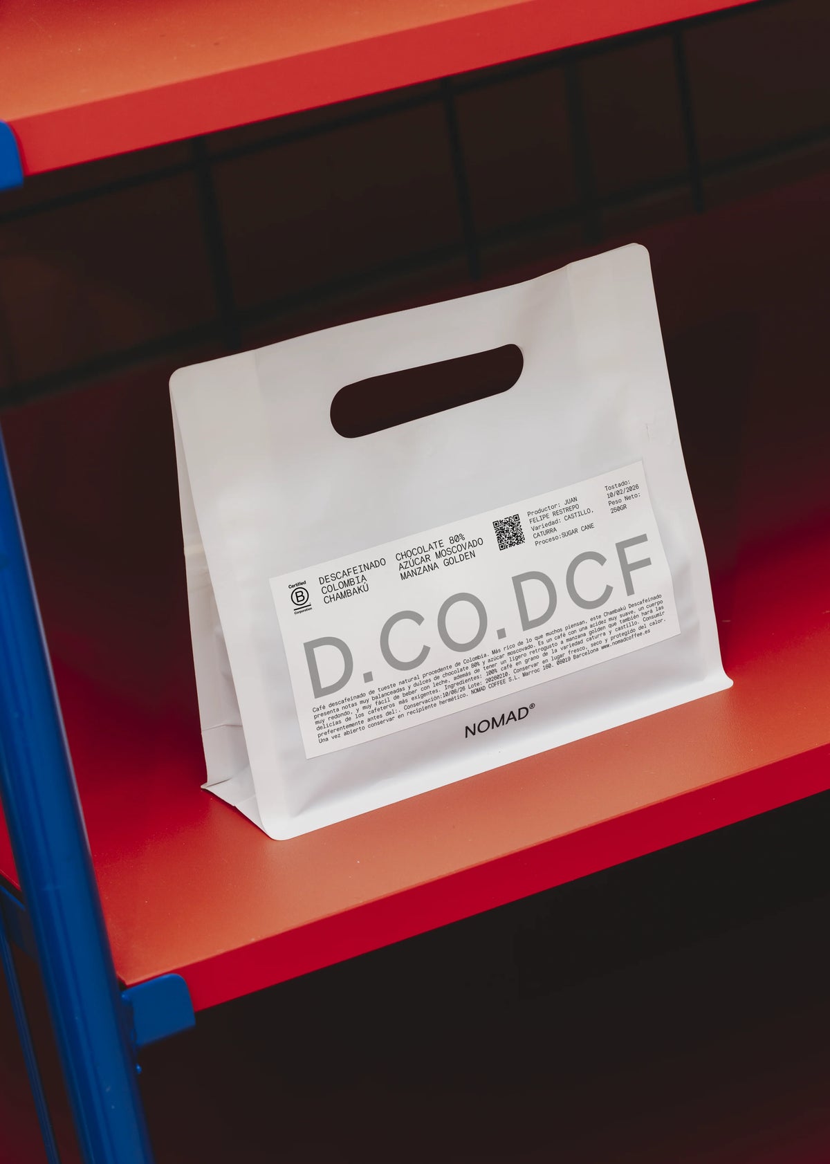A white paper coffee bag with a handle, featuring a white label printed with D.CO.DCF