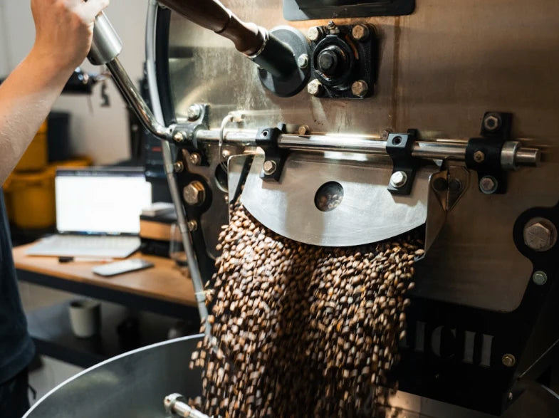 Freshly roasted coffee beans pouring out of a professional industrial coffee roaster.