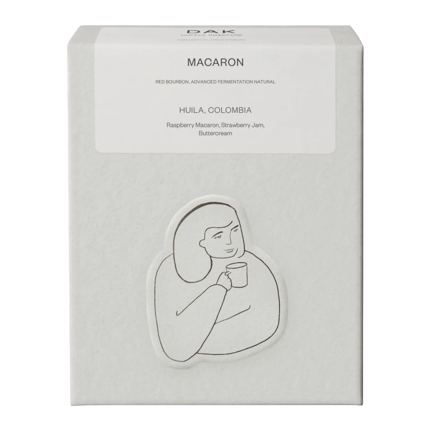 Vit kartong från DAK Coffee Roasters "Colombia Macaron" filterkaffe hela bönor med en svartvit illustration av en person