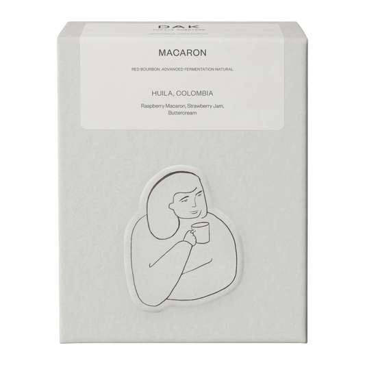 Vit kartong från DAK Coffee Roasters "Colombia Macaron" filterkaffe hela bönor med en svartvit illustration av en person