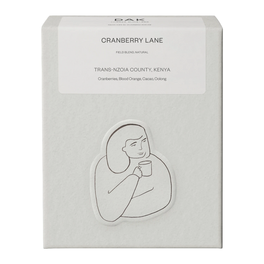 Vit låda DAK Coffee Roasters Kenya ”Cranberry Lane” med svartvit teckning av en person.