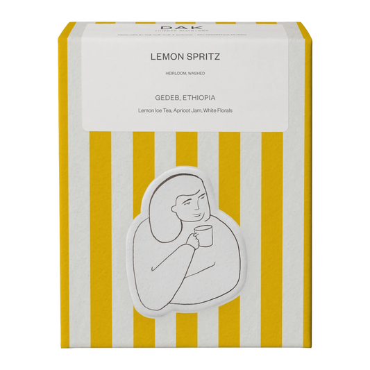 Yellow and white box of DAK Coffee Roasters Colombia Lemon Spritz Filter Whole Beans with gold on green drawing of a person