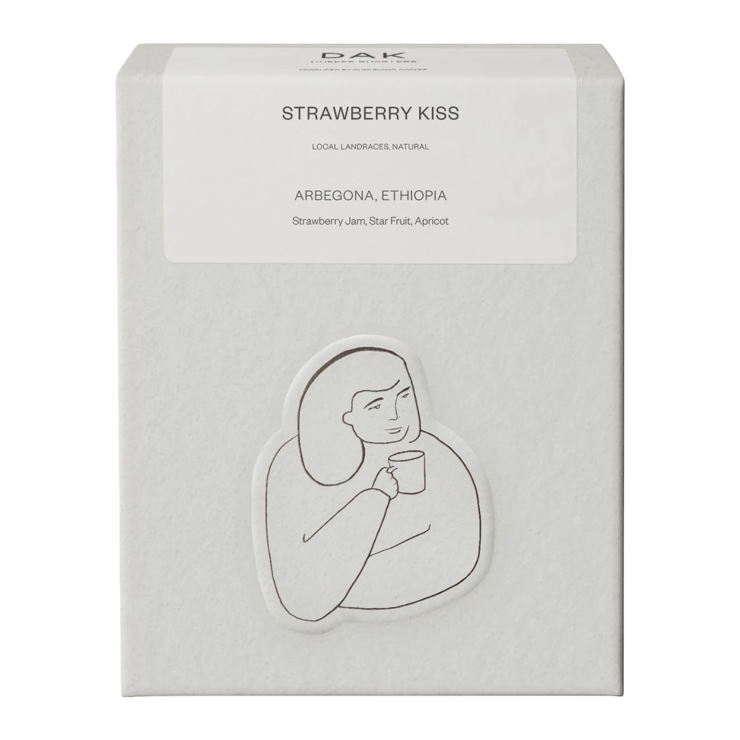 Vit låda DAK Coffee Roasters Ethiopia ”Strawberry Kiss” med svartvit teckning av en person.