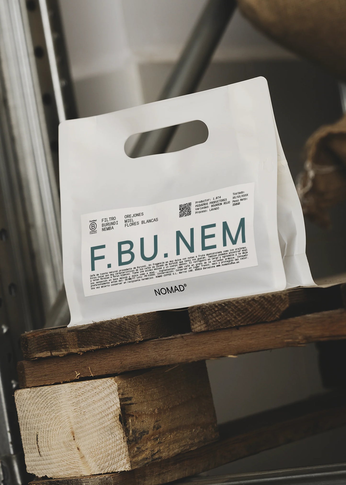 Vit kaffepåse i plast från Nomad Coffee med F.BU.NEM-etikett på en träyta