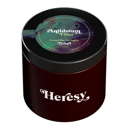En mörkröd cylindrisk burk med svart lock som visar en "Heresy"-logotyp och en färgglad "Antidotum" filterkaffeetikett.