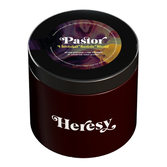 En mörkröd cylindrisk burk med svart lock som visar en "Heresy"-logotyp och en färgglad "Pastor" omniroast kaffeblandning.