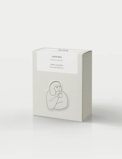 Vit kaffeförpackningslåda från DAK Coffee Roasters med texten "Juice Box" på vit bakgrund