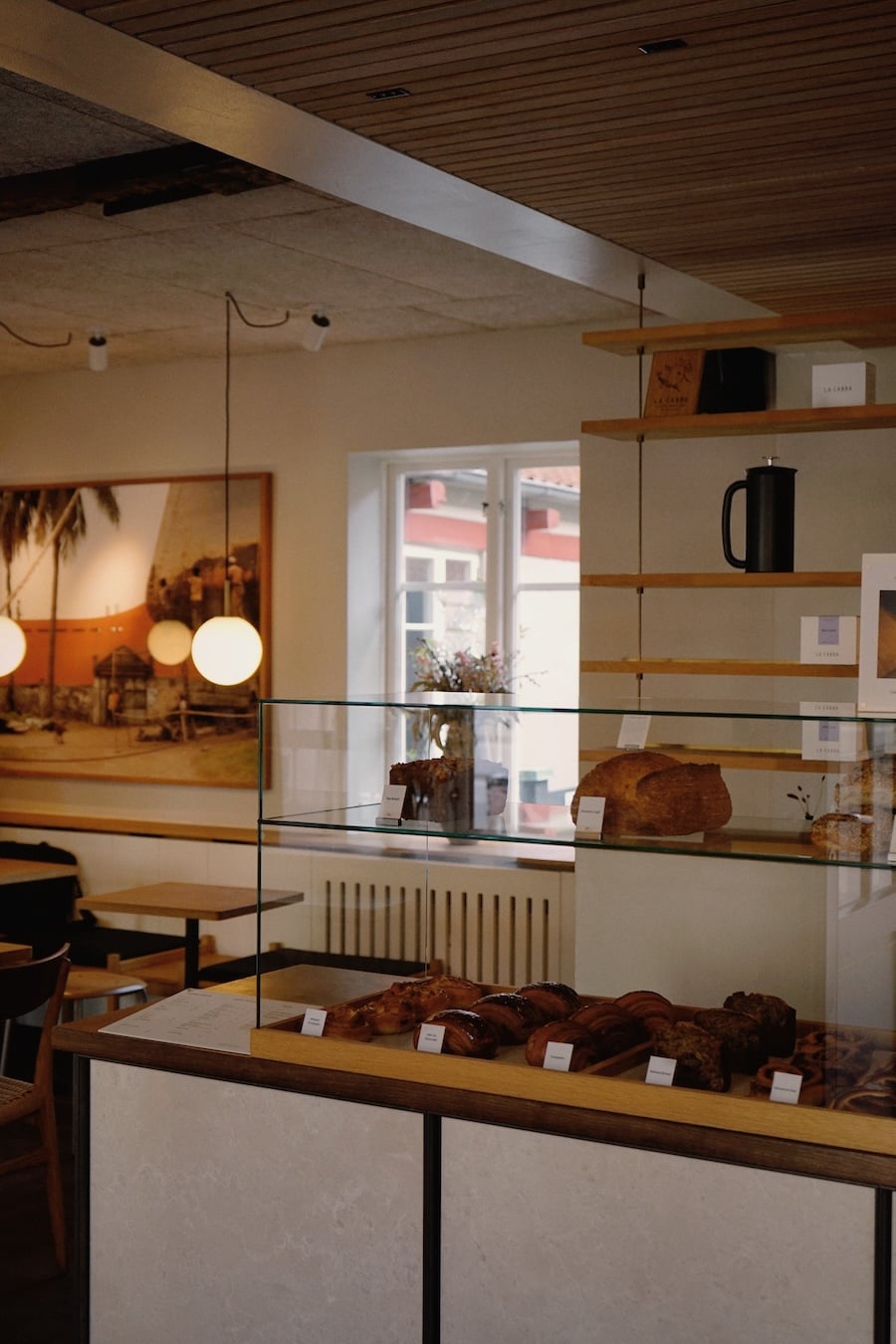Pastries and fresh bread displayed in a glass counter at La Cabra bakery.