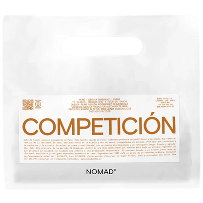 En vit påse av märket NOMAD med en framträdande orange etikett med texten "COMPETICIÓN" och mindre spansk text, fotograferad mot en enfärgad vit bakgrund.
