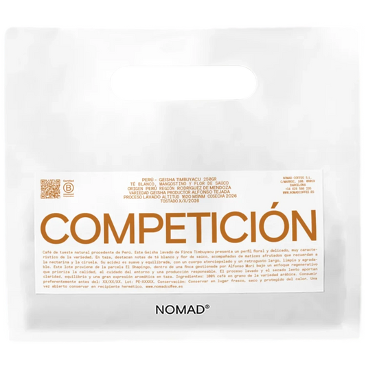 En vit påse av märket NOMAD med en framträdande orange etikett med texten "COMPETICIÓN" och mindre spansk text, fotograferad mot en enfärgad vit bakgrund.