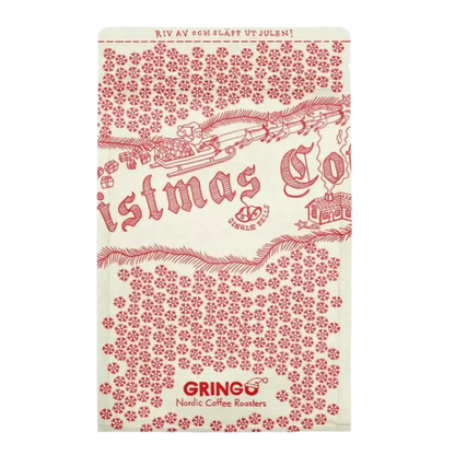 En rektangulär krämvit kaffepåse tryckt med en röd jul-temadesign som visar ett tåg, snö, granar och texten 'Christmas Co' och 'GRINGO Nordic Coffee Roasters'.