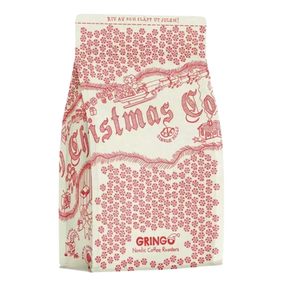 En påse svenskt julkaffe med ett rött och krämvitt mönster med illustrationer av en släde, ren och snöflingor, på en vanlig vit bakgrund.