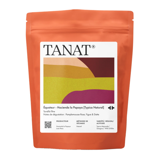 En ståpåse med TANAT Equador filterkaffe, med en skarp orangebrun påse med en stor vit etikett som innehåller en färgglad geometrisk grafik.
