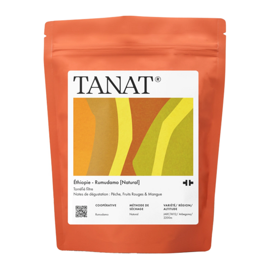 En levande orange ståpåse med TANAT Etiopien - Rumudamo (Natural)-kaffe, med en stor vit etikett med färgglad geometrisk grafik.