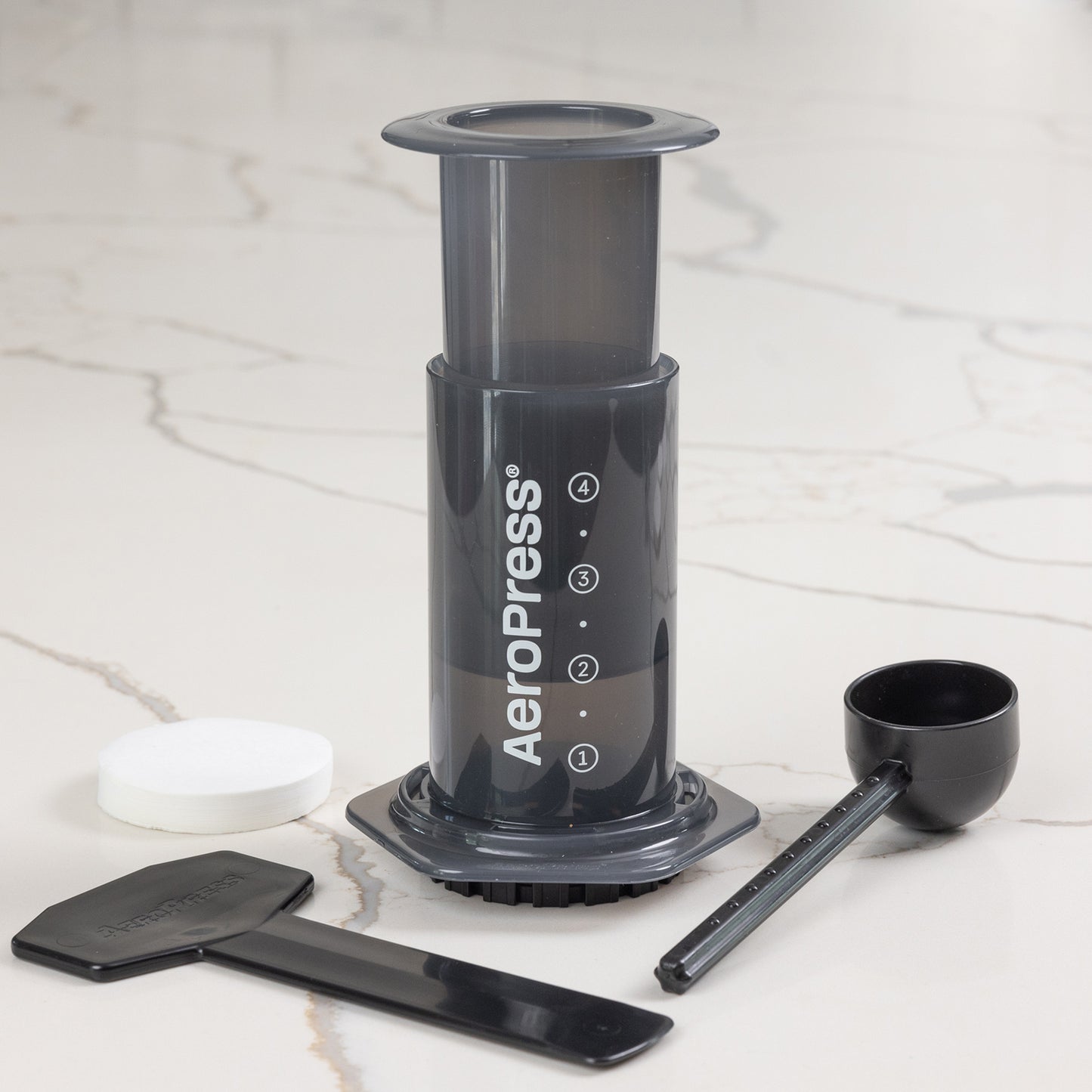 AeroPress Original set med pappersfilter, måttskopa och omrörare på en marmoryta