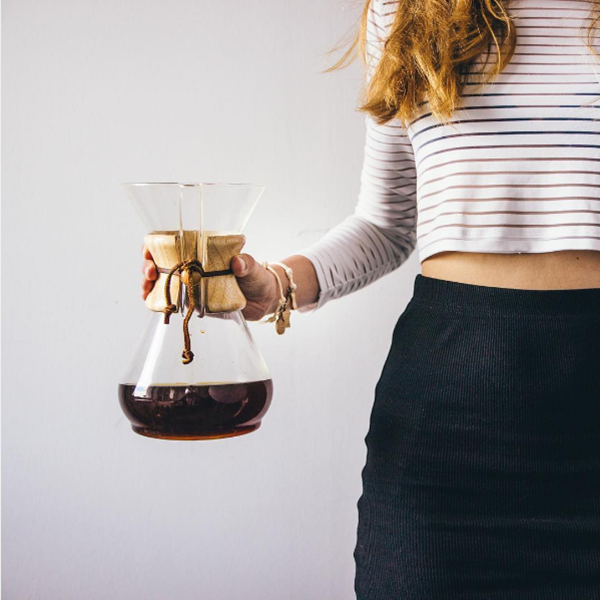 Person holding a glass coffee maker with a white background