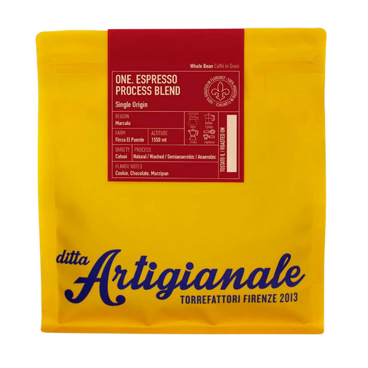 A yellow coffee bag with a red label at the top and large blue 'ditta Artigianale' branding near the bottom, photographed on a white background.