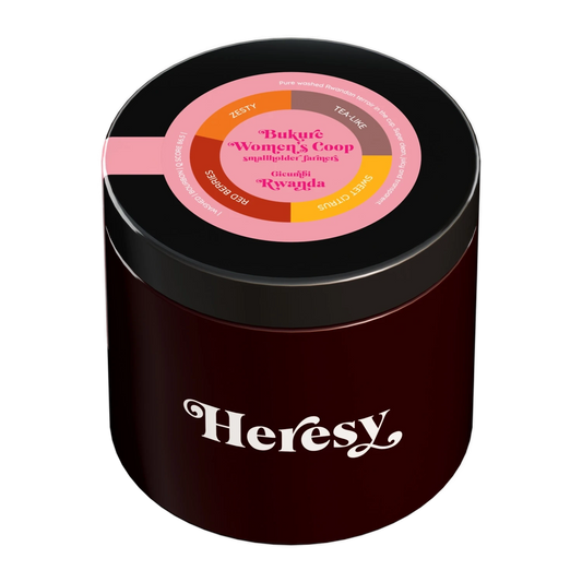 En mörkröd cylindrisk burk med svart lock som visar en "Heresy"-logotyp och en färgglad toppetikett för "Bukure Women's Coop".