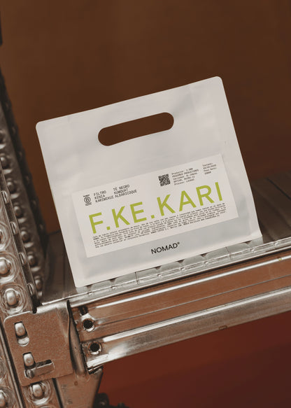 A white paper shopping bag with a handle and a printed label reading F.KE.KARI.