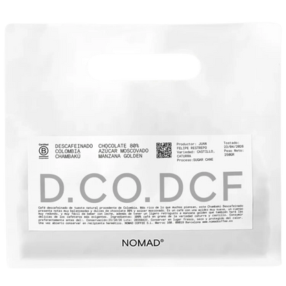 A white stand-up pouch of NOMAD Chocolate 80% Descafeinado Colombia Chambaku, featuring a white label with black and gray text and a QR code.