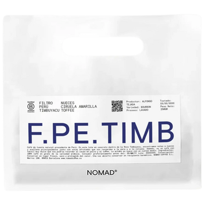 A white bag of NOMAD brand coffee with a prominent white label featuring the brand name 'F.PE.TIMB'.