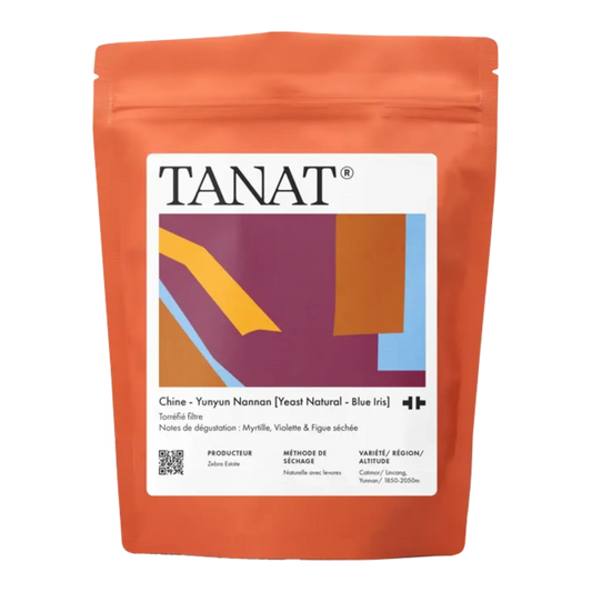 A stand-up pouch of TANAT China - Yunyun Nannan [Yeast Natural - Blue iris] tea, featuring a bright orange body with a large white label containing abstract geometric shapes in purple, yellow, blue, and brown.